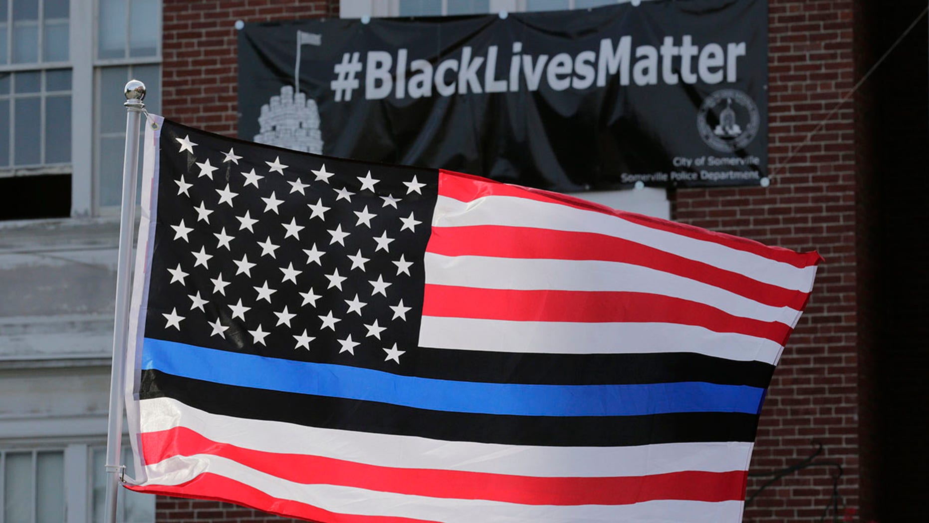 The Blue Lives Matter flag flying in front of a banner that says 'Black Lives Matter.'